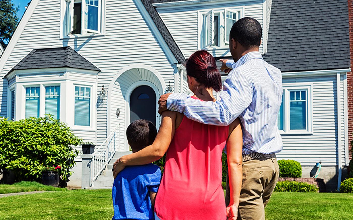 Family standing in front of a house and gazing at it